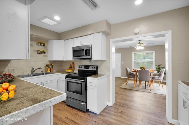 kitchen with decorative backsplash, white cabinets, appliances with stainless steel finishes, and sink