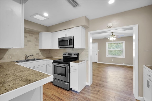 kitchen featuring white cabinetry, stainless steel appliances, tasteful backsplash, light hardwood / wood-style floors, and sink