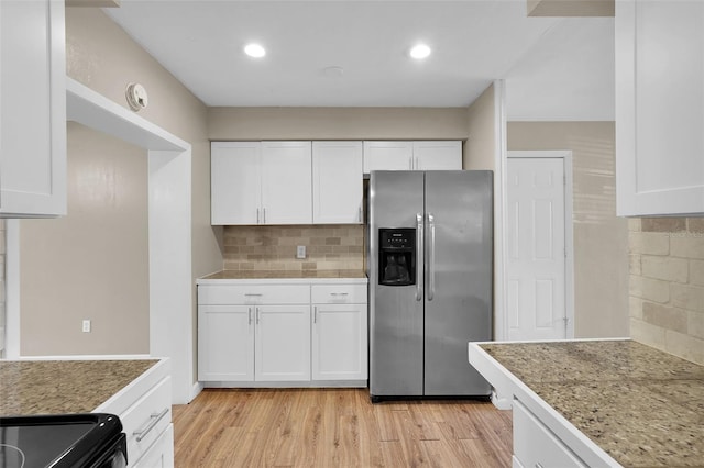 kitchen featuring white cabinets, light hardwood / wood-style floors, decorative backsplash, and stainless steel fridge