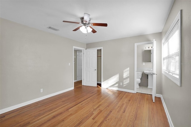 unfurnished bedroom featuring ensuite bathroom, light hardwood / wood-style floors, a closet, sink, and ceiling fan