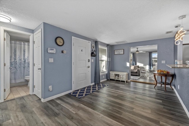 foyer with a textured ceiling, ceiling fan, and dark hardwood / wood-style floors