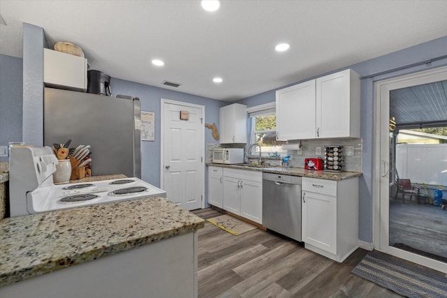 kitchen featuring white cabinetry, sink, stainless steel appliances, light stone counters, and hardwood / wood-style flooring