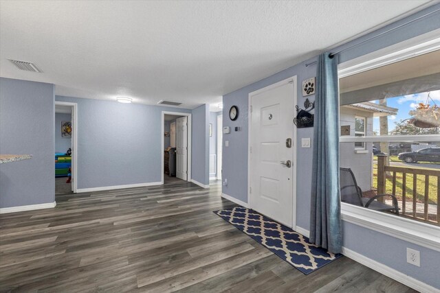 foyer entrance featuring a textured ceiling and dark hardwood / wood-style floors