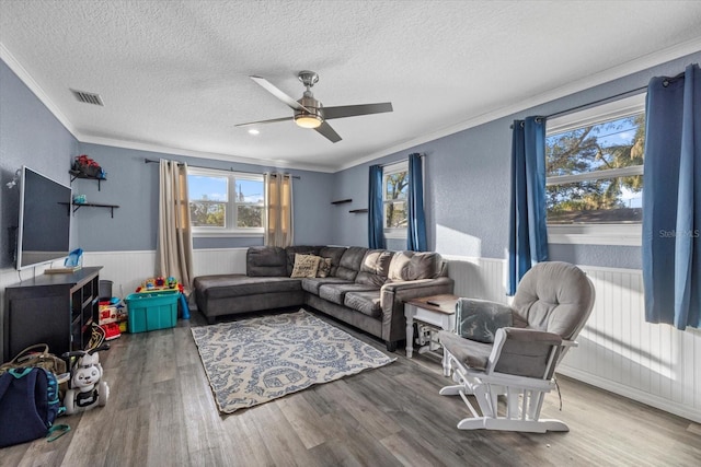 living room with ceiling fan, hardwood / wood-style floors, a textured ceiling, and ornamental molding