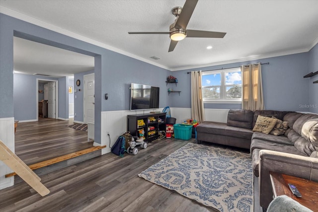 living room with ceiling fan, crown molding, dark wood-type flooring, and a textured ceiling