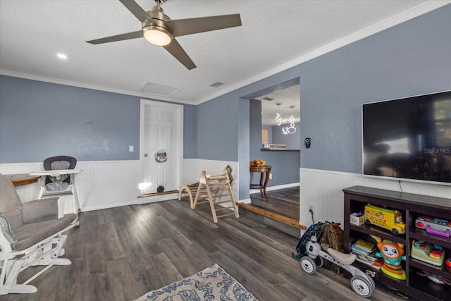 living area featuring a textured ceiling, dark hardwood / wood-style floors, ceiling fan, and crown molding