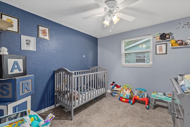 carpeted bedroom with a crib, a textured ceiling, and ceiling fan