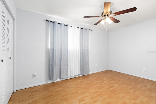 spare room featuring ceiling fan, light wood-style flooring, and baseboards