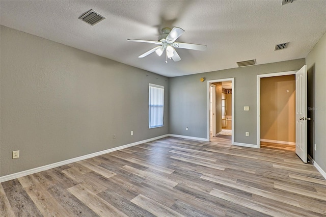 unfurnished bedroom featuring a textured ceiling, ensuite bathroom, light hardwood / wood-style flooring, and ceiling fan