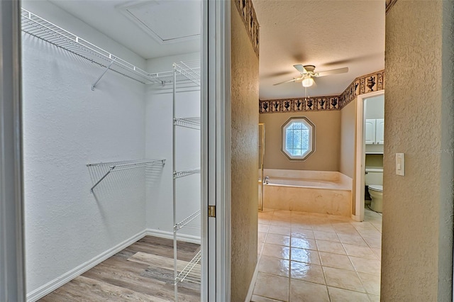 bathroom with a tub, ceiling fan, hardwood / wood-style floors, a textured ceiling, and toilet