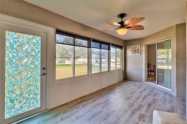 unfurnished sunroom featuring ceiling fan