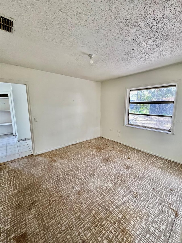 empty room featuring light tile patterned flooring and a textured ceiling