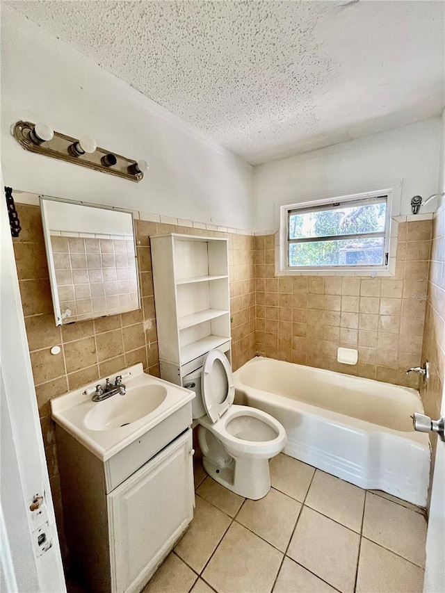 full bathroom featuring tile patterned floors, a textured ceiling, toilet, vanity, and tile walls