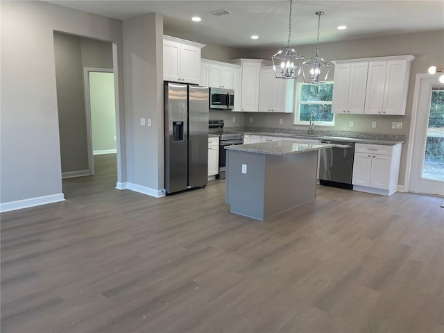 kitchen with white cabinetry, a kitchen island, stainless steel appliances, and decorative light fixtures