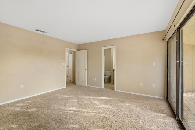 unfurnished bedroom with light carpet and connected bathroom