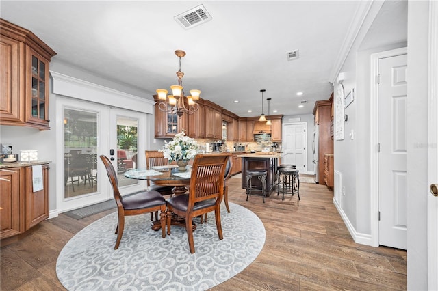 dining space with crown molding, dark hardwood / wood-style floors, and an inviting chandelier