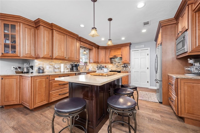 kitchen with a center island, tasteful backsplash, dark hardwood / wood-style floors, pendant lighting, and appliances with stainless steel finishes