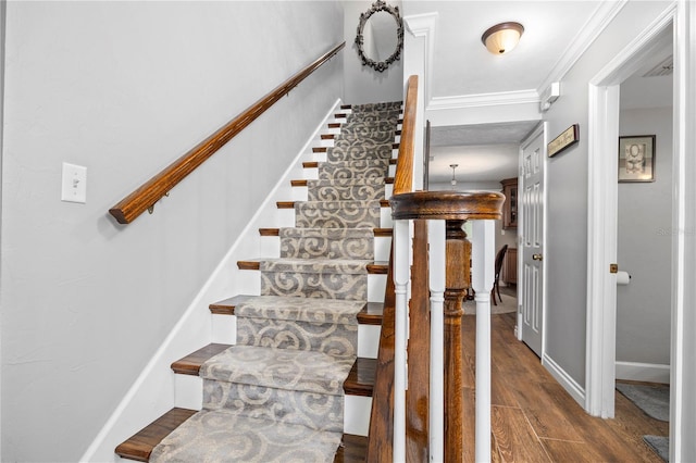 stairs with crown molding and wood-type flooring