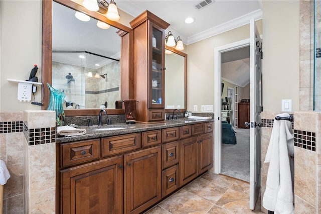 bathroom with a shower with door, vanity, tile walls, and ornamental molding