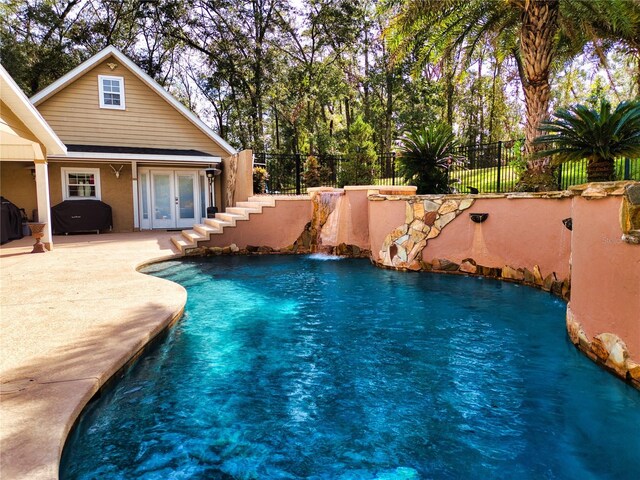 view of pool with pool water feature and french doors