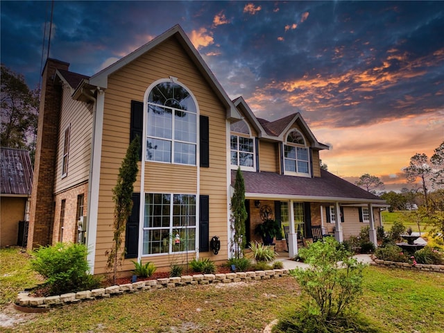 view of front of property featuring covered porch and a lawn