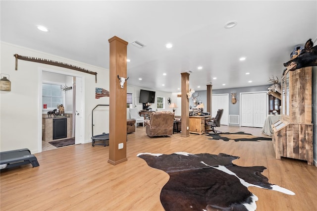 interior space with ornate columns, crown molding, and light hardwood / wood-style flooring