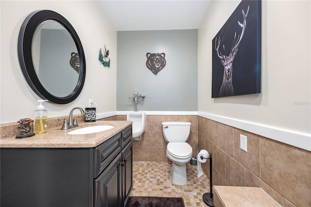 bathroom featuring tile patterned floors, vanity, toilet, and tile walls