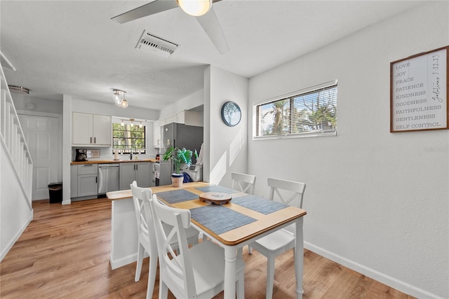 dining space with ceiling fan, sink, and light hardwood / wood-style flooring