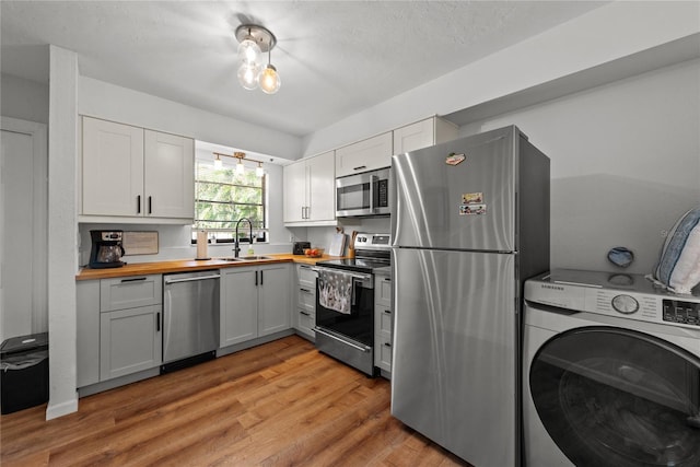 kitchen featuring wood counters, washer / dryer, stainless steel appliances, and white cabinetry