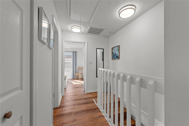 hallway featuring light wood-type flooring and a textured ceiling