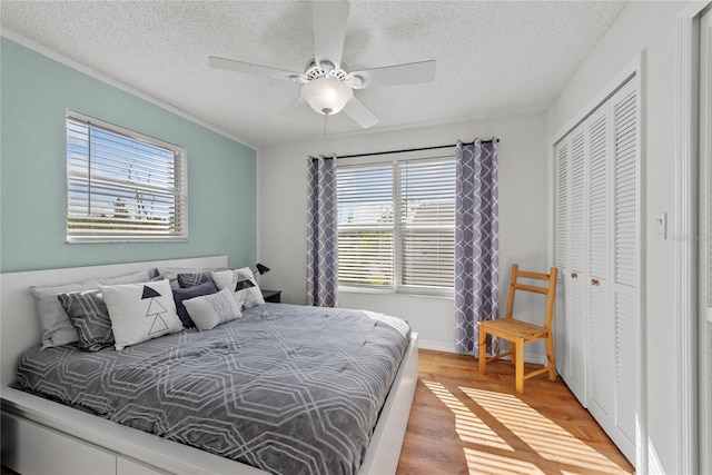 bedroom featuring a textured ceiling, light wood-type flooring, a closet, and ceiling fan