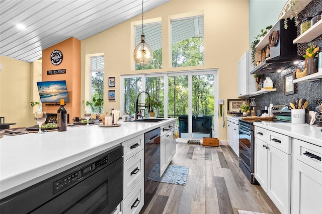 kitchen featuring white cabinetry, range with electric cooktop, sink, light hardwood / wood-style floors, and decorative light fixtures