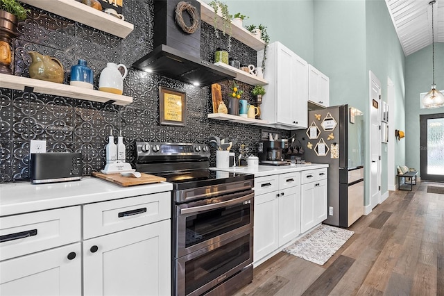 kitchen with wall chimney exhaust hood, hanging light fixtures, stainless steel appliances, dark hardwood / wood-style floors, and white cabinets