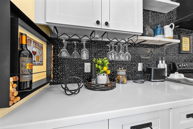 interior space featuring tasteful backsplash, white cabinetry, and range