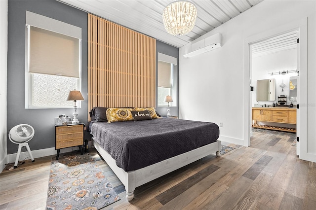 bedroom featuring ensuite bath, wood ceiling, a notable chandelier, and hardwood / wood-style flooring