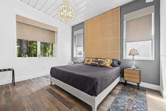 bedroom featuring wood-type flooring, wood ceiling, and an inviting chandelier