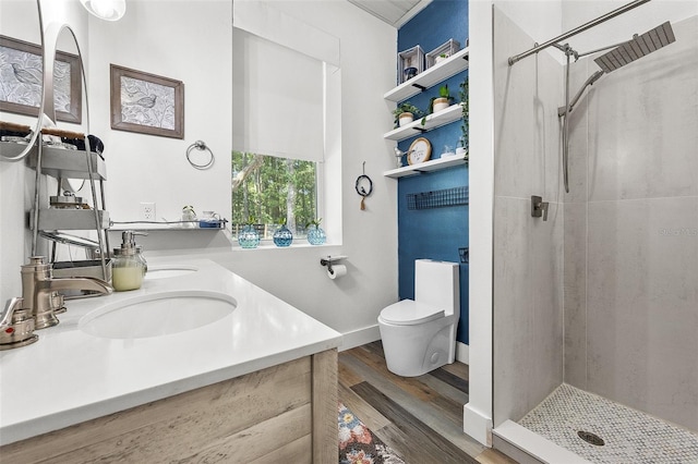 bathroom with toilet, vanity, wood-type flooring, and tiled shower