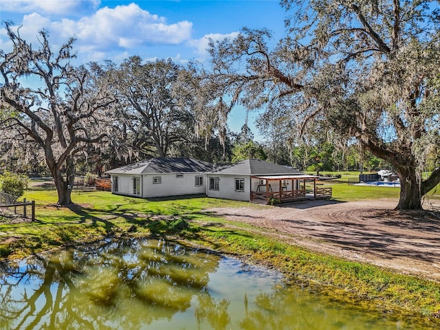 back of property with a yard and a water view