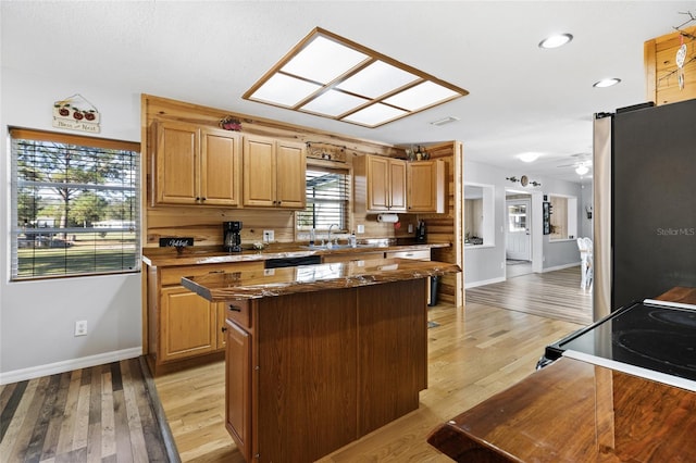 kitchen with ceiling fan, light hardwood / wood-style flooring, a kitchen island, and sink