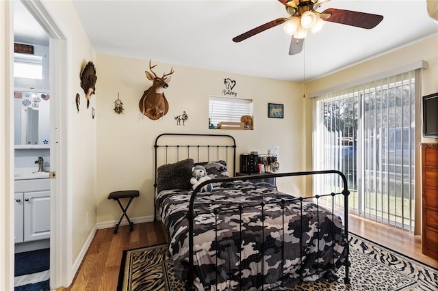 bedroom with multiple windows, ceiling fan, sink, and dark hardwood / wood-style floors