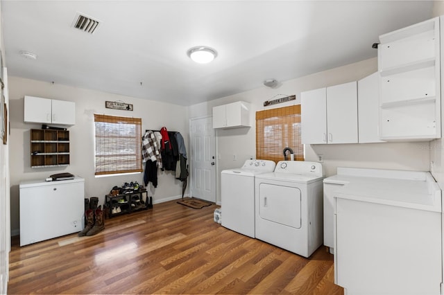 washroom with cabinets, independent washer and dryer, and dark wood-type flooring