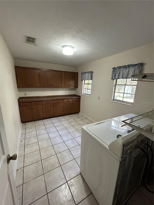 laundry area featuring washer and clothes dryer, light tile patterned flooring, cabinets, and a textured ceiling