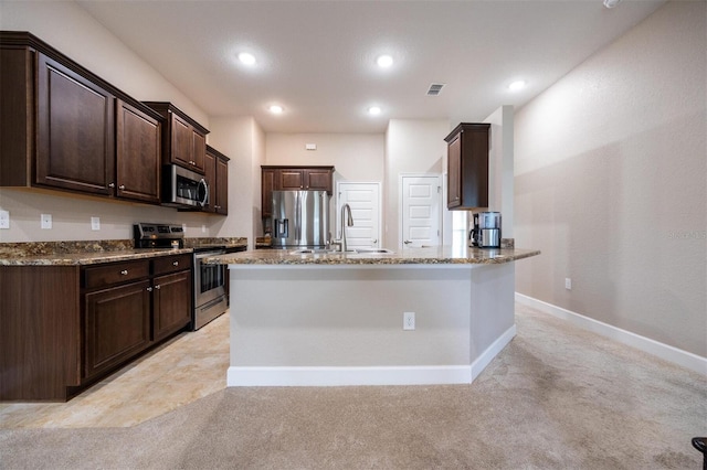 kitchen featuring dark brown cabinetry, sink, light colored carpet, and stainless steel appliances