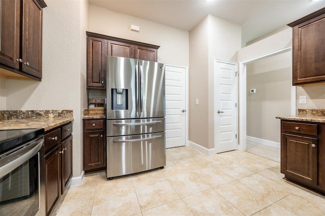 kitchen featuring dark brown cabinets, light tile patterned floors, stainless steel appliances, and stone counters