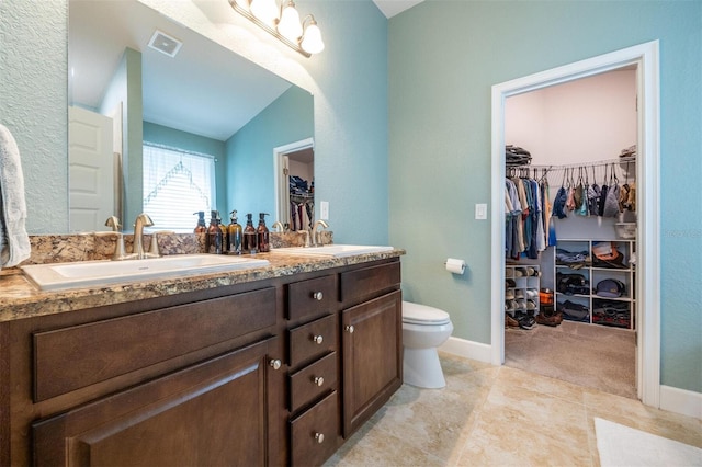 bathroom with tile patterned floors, vanity, lofted ceiling, and toilet