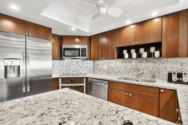 kitchen with light stone countertops, sink, ceiling fan, appliances with stainless steel finishes, and ornamental molding