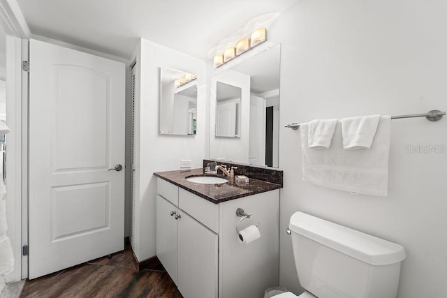 bathroom featuring wood-type flooring, vanity, and toilet