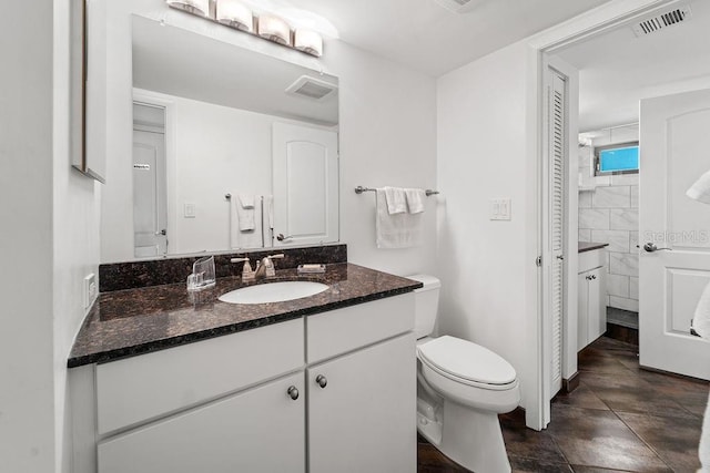 bathroom with toilet, vanity, and tile patterned floors