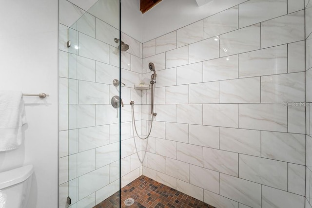 bathroom with toilet and a tile shower