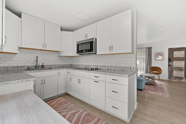 kitchen with backsplash, light hardwood / wood-style flooring, white cabinets, and sink